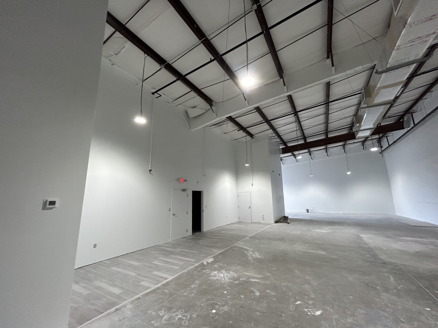 Completed commercial gym interior painting with tall white walls and exposed structure