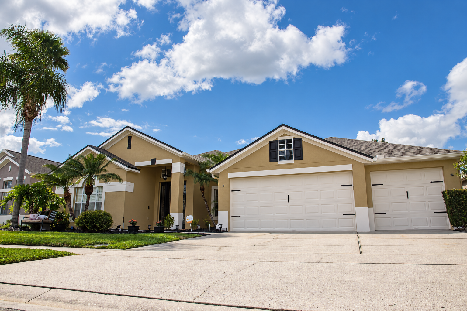 Completed tan residential exterior with crisp white trim and garage doors